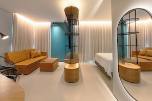 A modern hotel room with a sofa, a bed, a round wooden table, and a tall, cylindrical lamp. - Design and Modern Living in Downtown Maringa - NEO204 (Maringá)