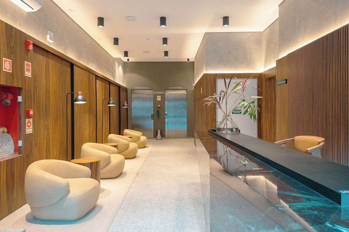 Um hall de hotel moderno com balcão de recepção, área de estar e elevadores.