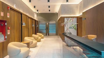 Um hall de hotel moderno com balcão de recepção, área de estar e elevadores.