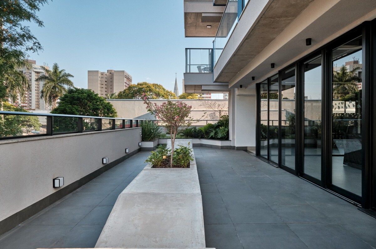 Um edifício moderno com telhado plano, grandes janelas e um pequeno jardim com plantas.