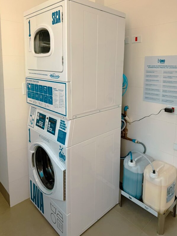 A stacked washer and dryer unit with a control panel, a water tank, and a hose.