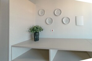 A minimalist room with a white desk, a potted plant, and wall-mounted plates with designs.