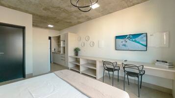 Un dormitorio moderno con cama, escritorio, sillas y un cuadro en la pared.