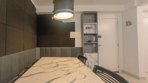 Ruokailutila, jossa on marmoripöytä, tuoleja, riippuvalaisin, seinään upotettu hylly ja ovi.