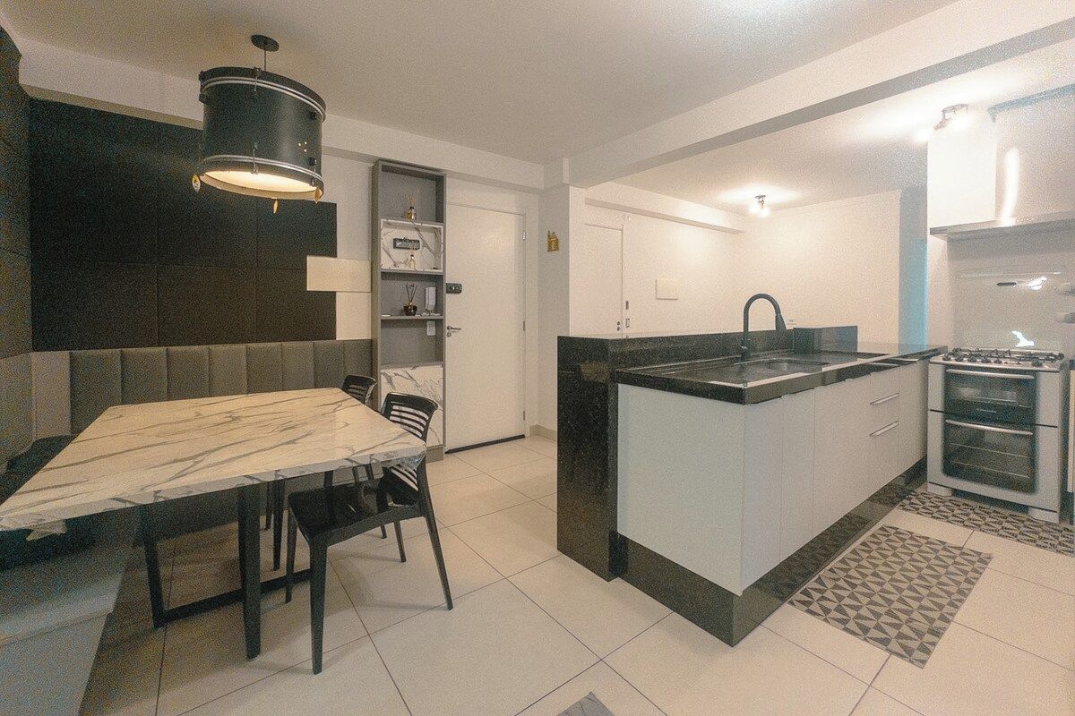 Een moderne keuken met een marmeren aanrecht, een inbouwfornuis en een eethoek met een tafel en stoelen.