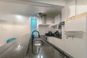 A modern kitchen with a stainless steel sink, a stove, and a refrigerator. - Spacious 3-Bedroom Family Apartment - AZ401-1 (Maringá)