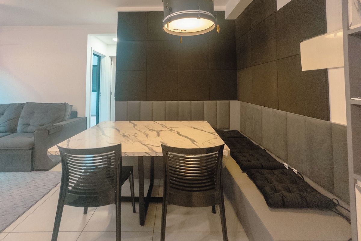 Een moderne eetruimte met een marmeren tafel, zwarte stoelen en een bank.