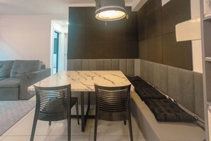 Uma área de refeições moderna com uma mesa de mármore, cadeiras pretas e um banco.