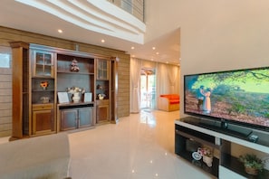 A modern living room with a flat-screen TV, wooden shelving, and a bright interior.