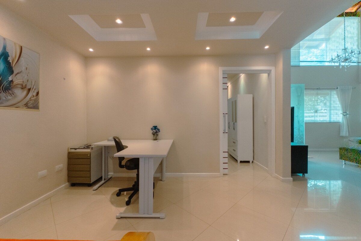 A modern office space with a desk, chair, and filing cabinet. There is a large window providing natural light and a view of the outdoors.