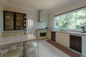 A modern kitchen with a granite countertop, stainless steel appliances, and a window providing a view of greenery.