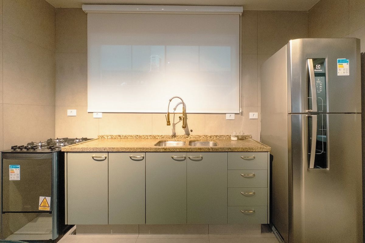 Una cocina con estufa a gas, pileta y refrigerador de acero inoxidable.