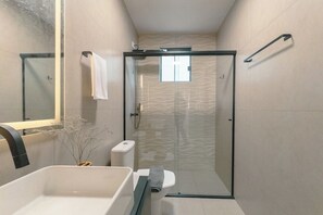 Un bagno moderno con doccia vetrata, vasca da bagno bianca e servizi igienici.