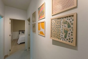 A hallway with a bed and artwork on the walls.