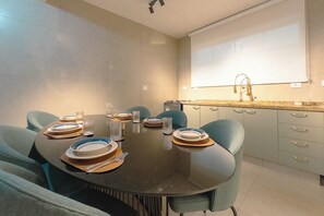 A modern dining area with a round table set for four, surrounded by teal chairs.