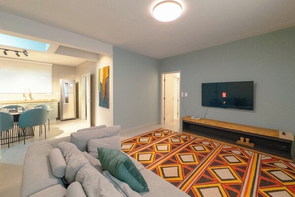 Un soggiorno moderno con un divano, un tappeto decorato e una TV a schermo piatto montata a parete.