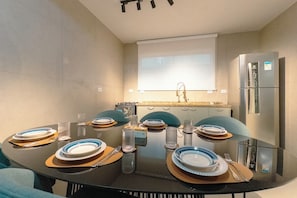 Una cucina moderna con un tavolo da pranzo per quattro persone, un frigorifero e una finestra sopra il lavello.