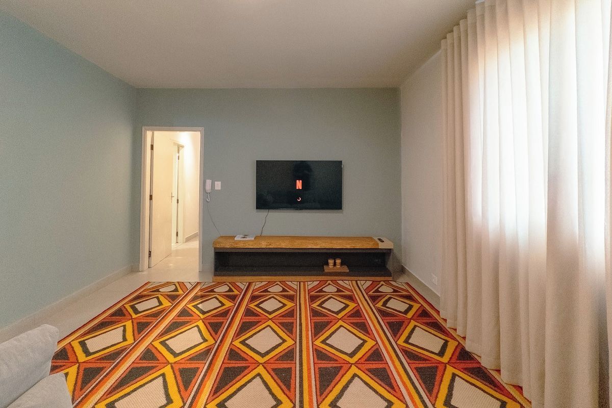 Une chambre à coucher avec un lit, un téléviseur fixé au mur et une porte donnant sur une autre pièce.