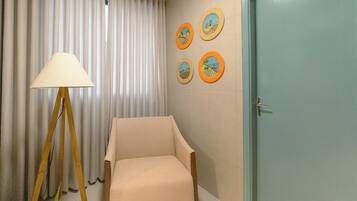 A room with a chair, a lamp, a door, and four framed pictures on the wall.