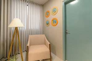 A room with a chair, a lamp, a door, and four framed pictures on the wall. - Bright Apartment by Praca dos Expedicionarios - HU337-101 (Maringá)