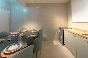 A modern kitchen with a dining table set for four, a built-in oven, and light-colored cabinetry.
