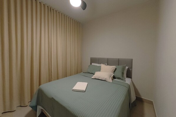 A bedroom with a bed, curtains, and a ceiling light.