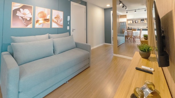 Ein modernes Wohnzimmer mit einem hellblauen Sofa, einem Holztisch und Wandbildern.