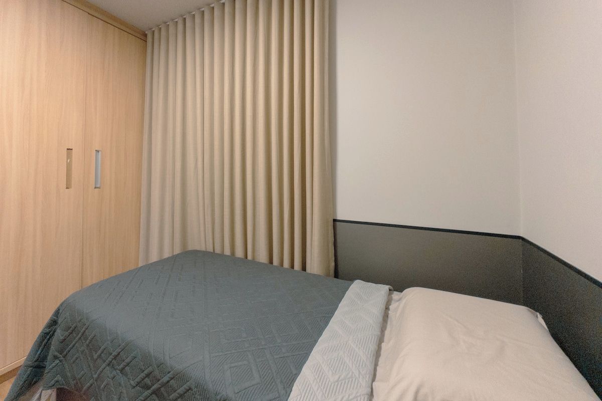 Een slaapkamer met een bed, een kledingkast en een raam met gordijnen.