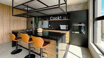 A modern kitchen with a central island, bar stools, and a large window.