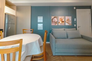 Un espacio habitable compacto con una mesa de comedor, un sofá y un refrigerador.