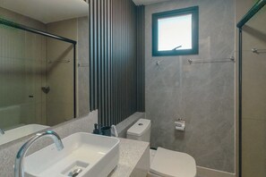 A modern bathroom with a large mirror, a rectangular sink, a toilet, and a shower enclosure. - Beautiful Modern Apartment in Zona 7 - BEDEO901 (Maringá)