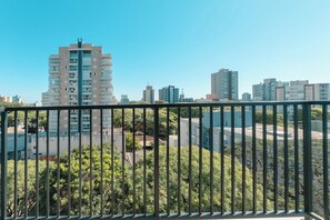 Un edificio alto de diseño moderno, rodeado de vegetación y otros edificios residenciales.
