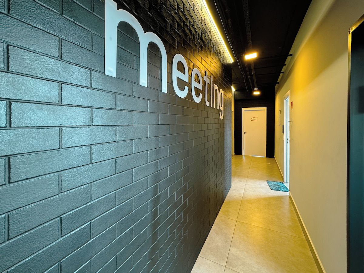 A hallway with a dark brick wall and a sign that reads 'meeting'.