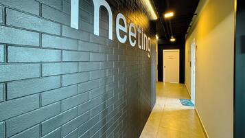 A hallway with a dark brick wall and a sign that reads 'meeting'.