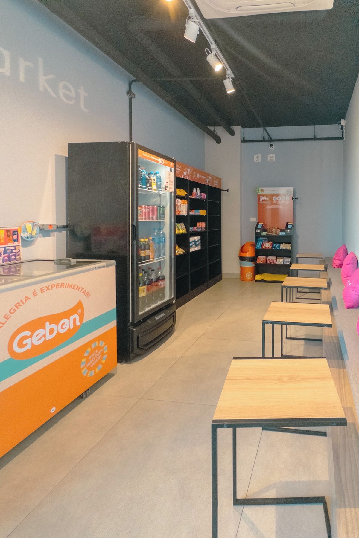 A modern interior with a refrigerated display, shelves stocked with products, and a seating area with tables and chairs.