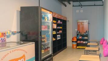 A modern interior with a refrigerated display, shelves stocked with products, and a seating area with tables and chairs.