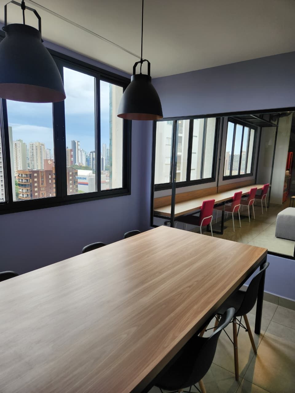 A conference room with a long table, chairs, and pendant lighting.