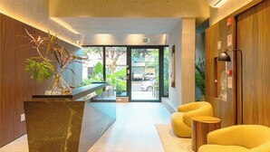 A reception area with a marble counter, a potted plant, and yellow seating.