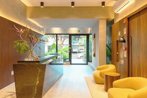 A reception area with a marble counter, a potted plant, and yellow seating.