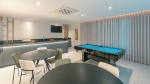 A modern indoor space with a pool table, bar area, and seating.