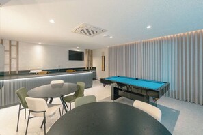 A modern indoor space with a pool table, bar area, and seating.