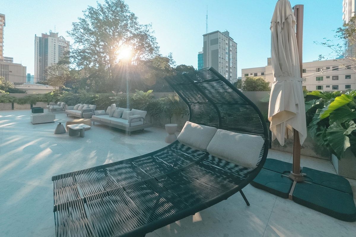 Een terras op het dak met een zwarte lounge fauteuil, een bank en een tafel.