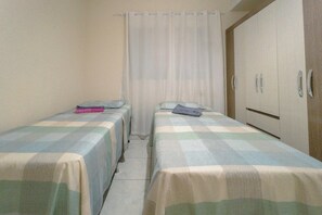 Ein Zimmer mit zwei Einzelbetten, einem Kleiderschrank und einem Vorhang.