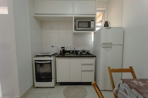 Kompakti keittiö, jossa on liesi, mikroaaltouuni ja jääkaappi.