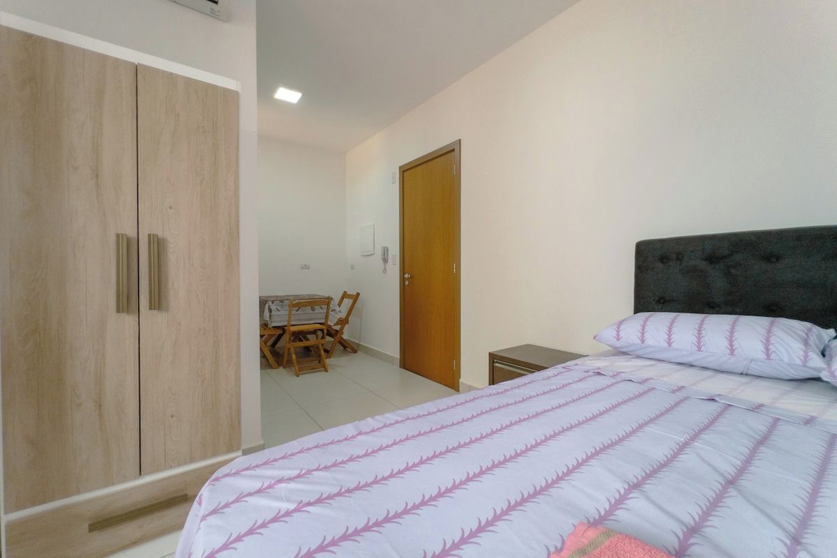 Un dormitorio con cama, armario, escritorio y sillas, además de una puerta.