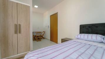 Un dormitorio con cama, armario, escritorio y sillas, además de una puerta.