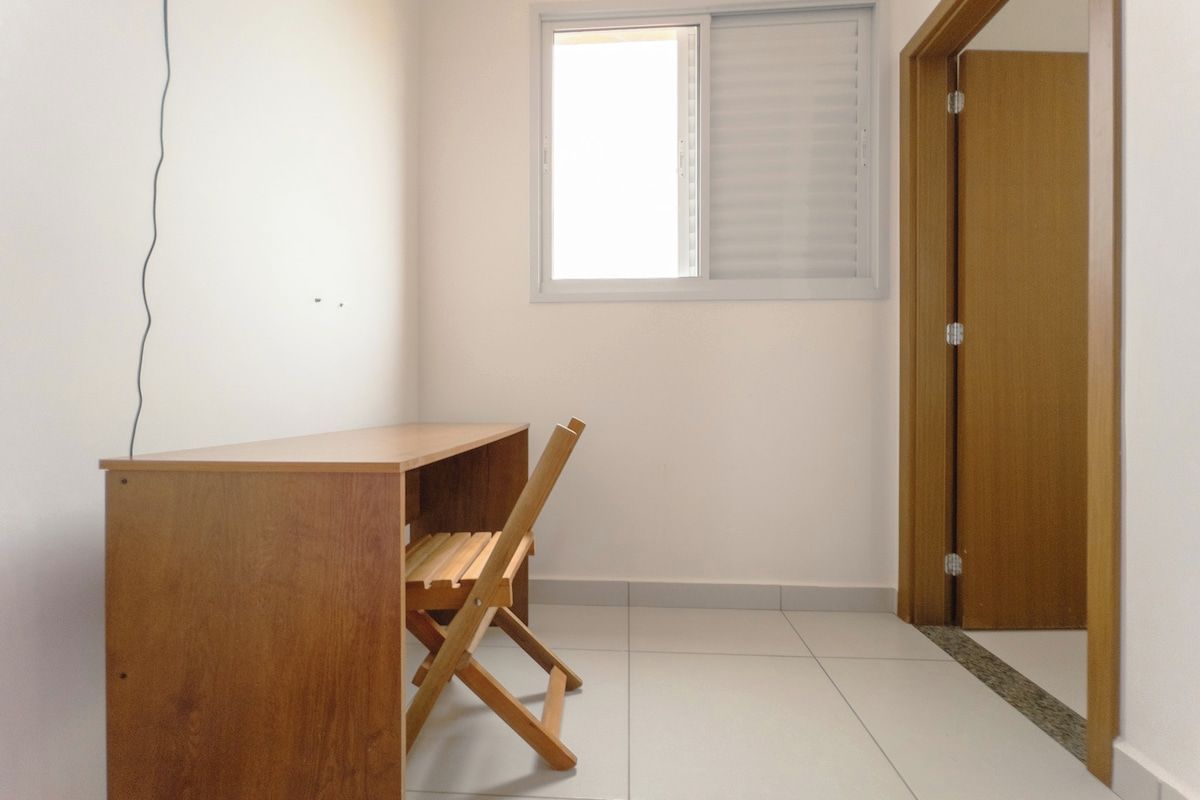 Una habitación con un escritorio de madera, una ventana con persianas y una puerta.
