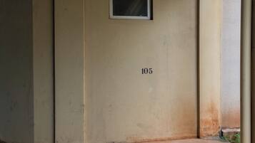 A beige wall with the number 105, a small window, and a concrete floor.