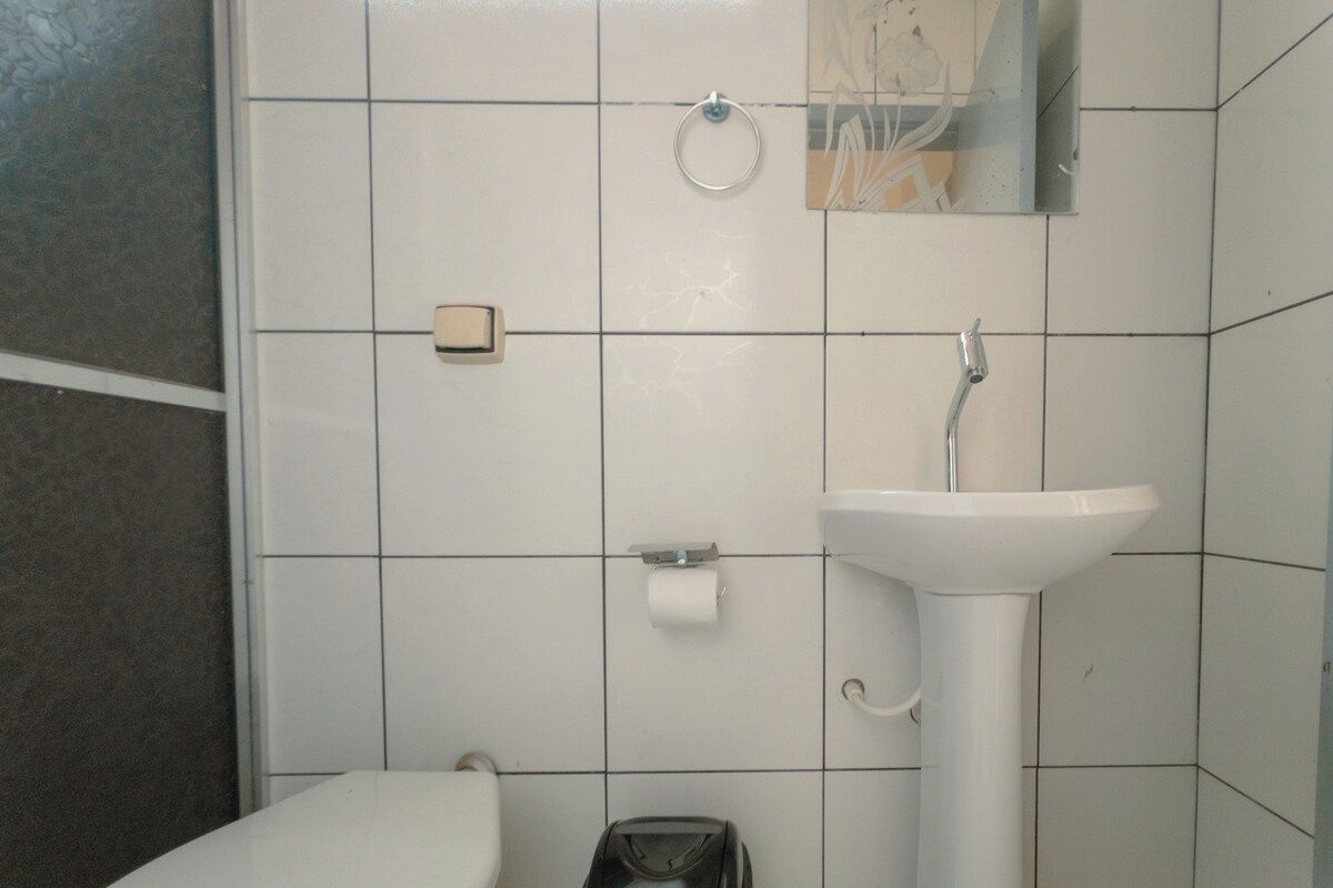 Un baño con lavamanos blanco, inodoro y espejo sobre el lavamanos.