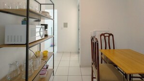 Una cuina amb taula i caires de fusta, un refrigerador blanc i prestatges amb vaixella.